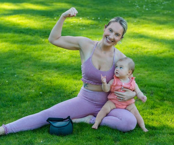 Young mother with her baby nearby sitting on a yoga mat.